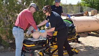 三名学生在救护车担架上用假人进行户外训练. 太阳集团娱乐场登陆网站紧急医疗救护员证书